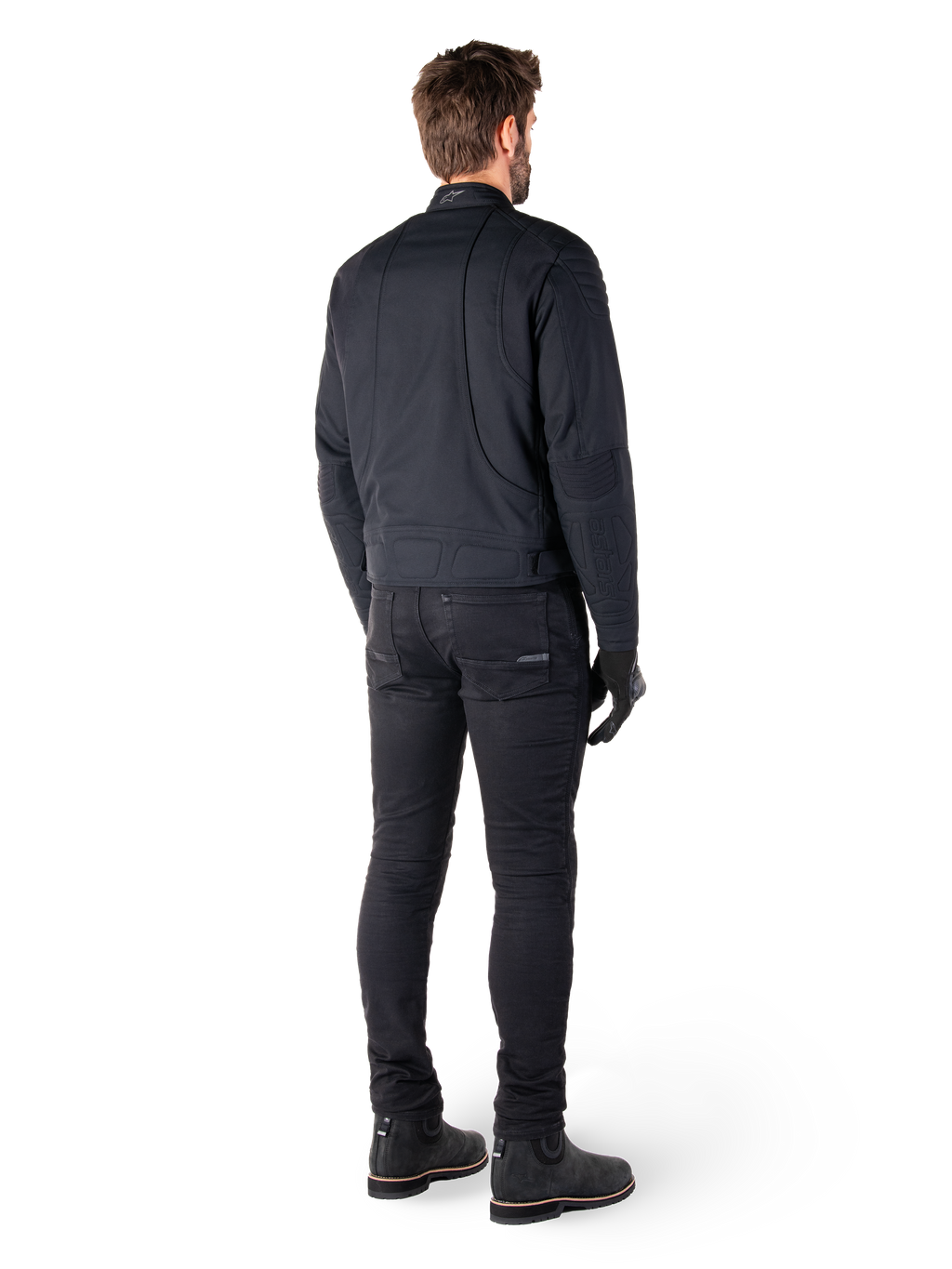 Rückansicht eines Fahrers in der schwarzen Alpinestars Clayton WR Jacke, mit gesteppten Paneelen an Ellbogen und Schultern, ergonomisch geschwungenen Nähten und reflektierenden Details am Kragen, kombiniert mit schwarzer Motorradhose und Stiefeln für einen urbanen Look.