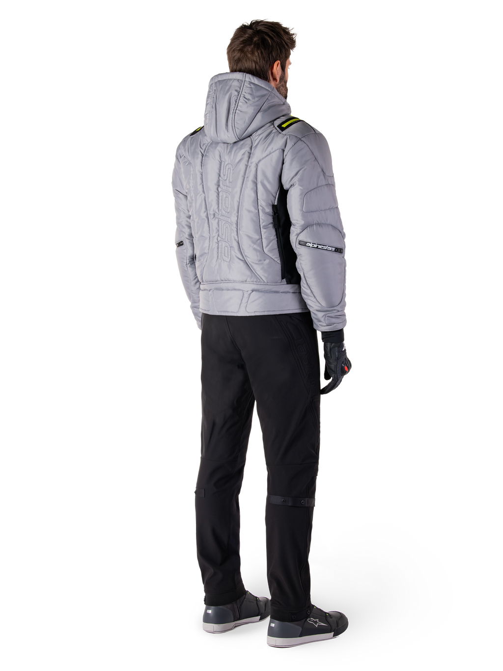 Alpinestars Mohobbs Wasserdichte Jacke, Lunar Gray Lime Punch, Rückansicht einer gesteppten Motorradjacke im Bomber-Stil mit Kapuze, mit Alpinestars-Schriftzug auf dem Rücken, getragen mit schwarzer Motorradhose und Handschuhen, urbane Moto-Streetwear