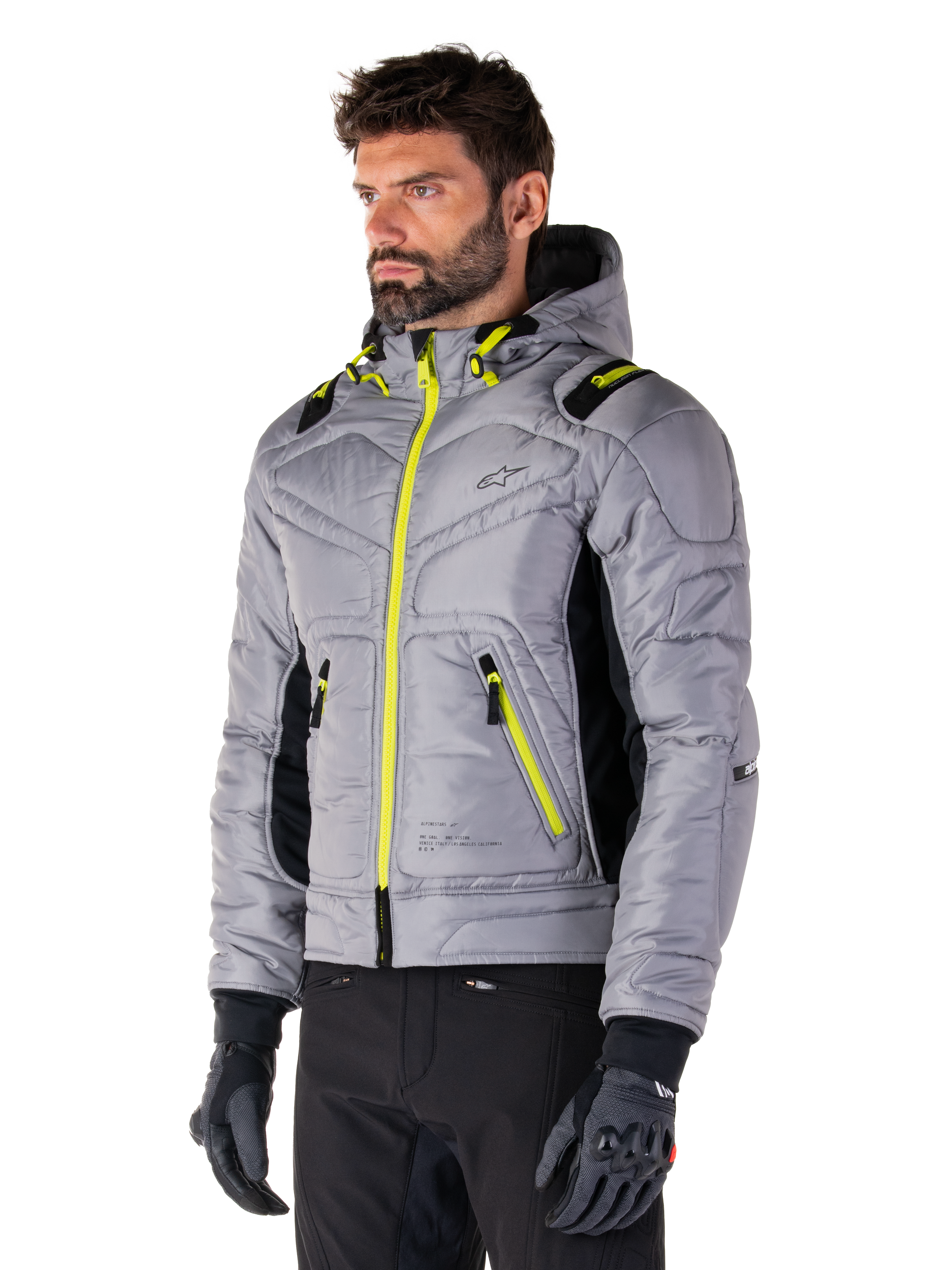Alpinestars Mohobbs Wasserdichte Jacke, Lunar Gray Lime Punch, gesteppte Bomber-Motorradjacke für Herren mit neongelben Reißverschlüssen und Kordelzug-Akzenten, getragen mit schwarzer Motorradhose und Handschuhen, modernes Urban-Moto-Streetwear-Design mit Kapuze