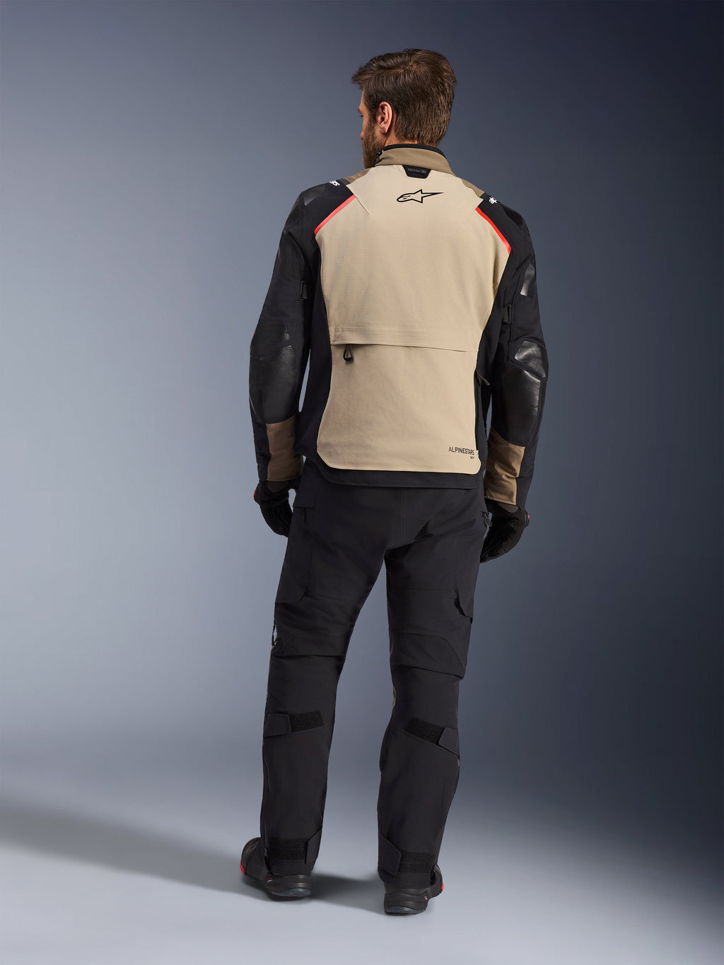 Alpinestars Andes Pro Drystar® XF Jacket, Walnut Aluminum, back view, motorcycle adventure jacket with black sleeves and red shoulder accents, worn with black riding pants and gloves.