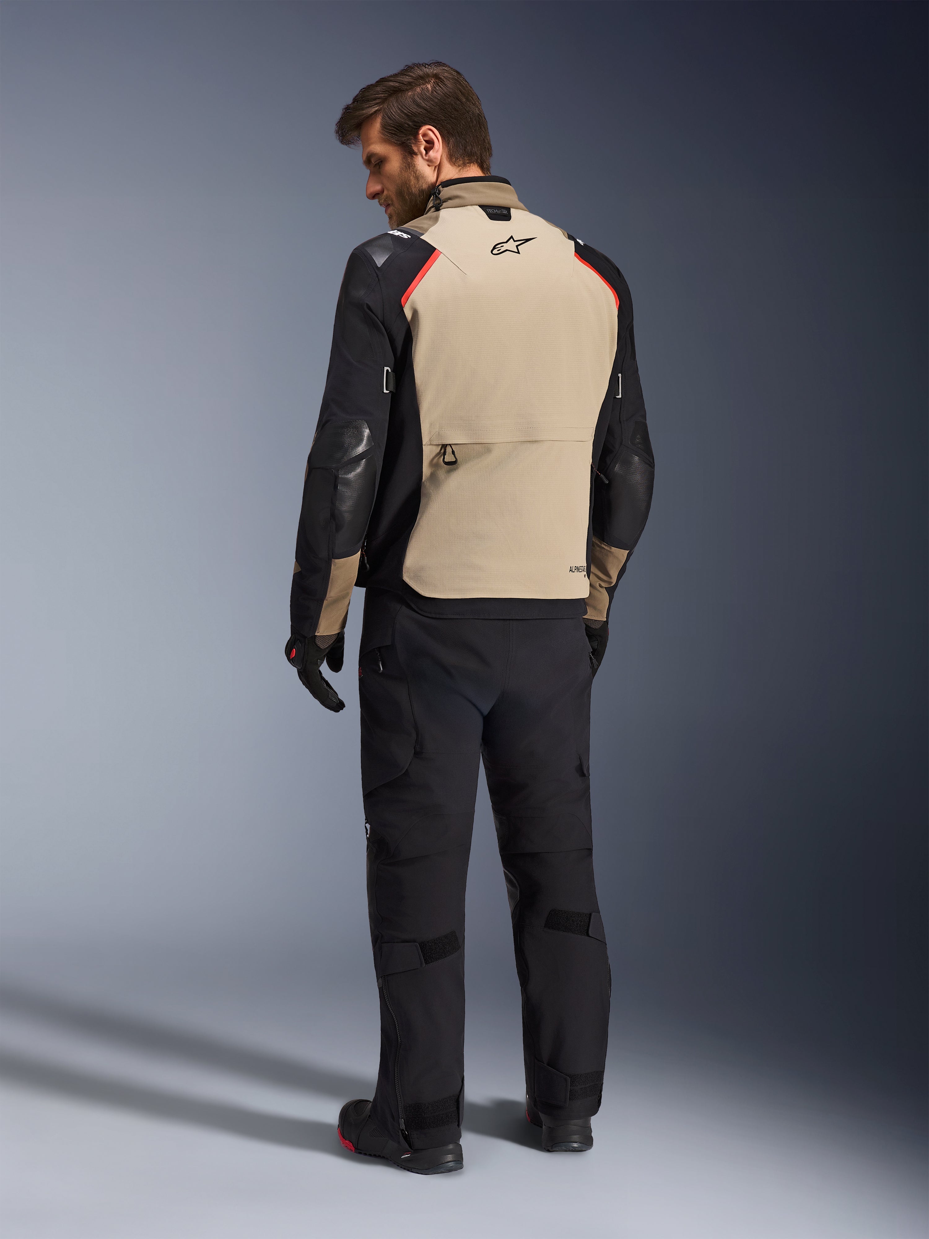 Alpinestars Andes Pro Drystar® XF Jacket, Motorcycle Jacket, Walnut and Black with red accents, back view on model, adventure touring design with large rear storage pocket, worn with black riding pants and gloves.