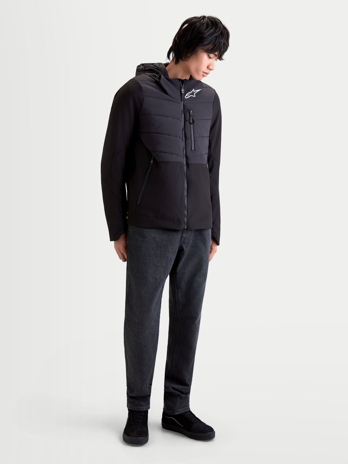 Alpinestars Therma Tech Wp Jacke, urbane Motorradjacke für Herren in Schwarz, Vorderansicht an einem Model, das die isolierte Textiljacke mit integriertem Kapuzensystem trägt