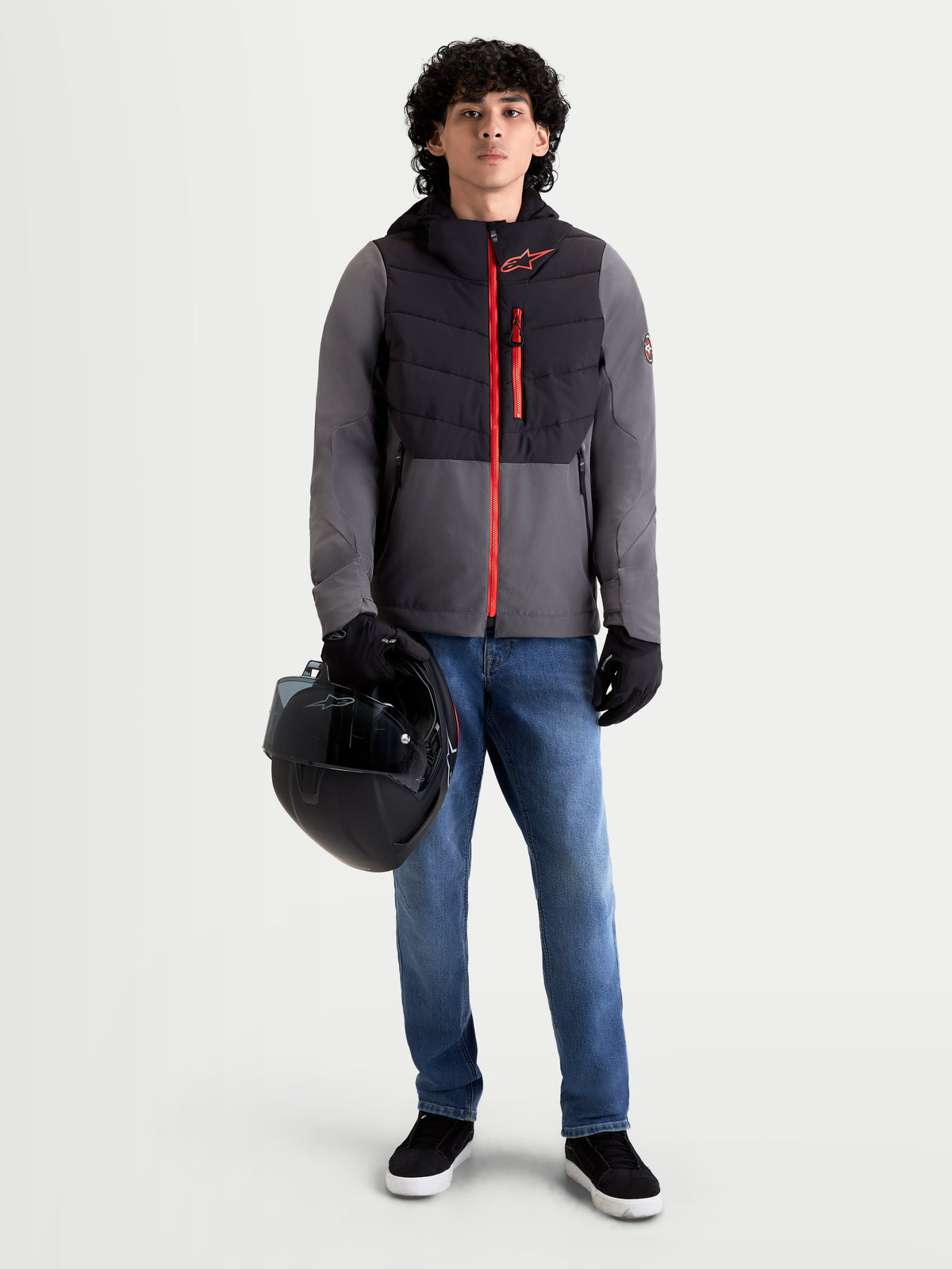 Alpinestars Therma-Tech Waterproof Jacket, men's urban motorcycle textile jacket in black and dark gray, front view on a model holding a helmet, featuring sonic-welded down construction and red accents