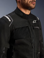 Close-up of the Alpinestars Cusco Drystar® Jacket in Black, featuring zippered mesh ventilation panels on the chest, white Alpinestars branding on the shoulder and chest, durable textile construction for motorcycle road adventure touring