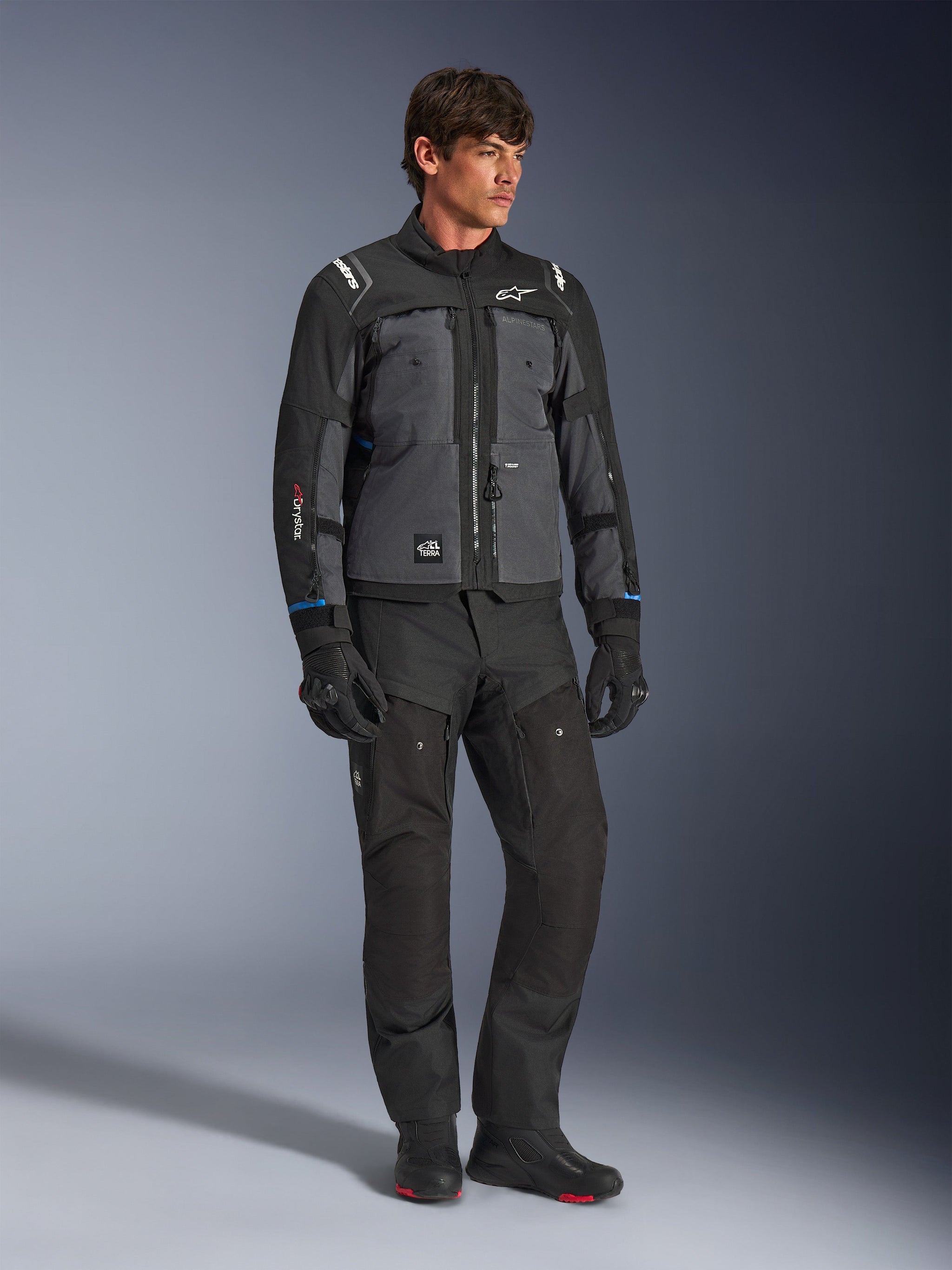 Alpinestars Cusco Drystar® Jacke in Schwarz und Dunkelgrau, technische Motorrad-Tourenjacke mit mehrfarbigen Paneelen, kombiniert mit passender schwarzer Hose und Handschuhen, konzipiert für Straßen- und Adventure-Touren.