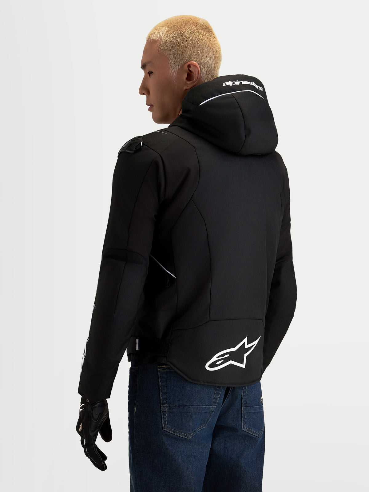 Alpinestars Zaca V2 Waterproof Jacket, men's black and white textile motorcycle jacket, rear view showing integrated hood with white Alpinestars branding, extended rear hem with large A-star logo, and shoulder protection details