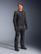 Male model wearing the Alpinestars ST-2 Air Jacket in black, featuring a red star logo and 'Alpinestars Exploration Equipment' branding, paired with matching black riding pants, gloves, and boots for a modern summer touring outfit.