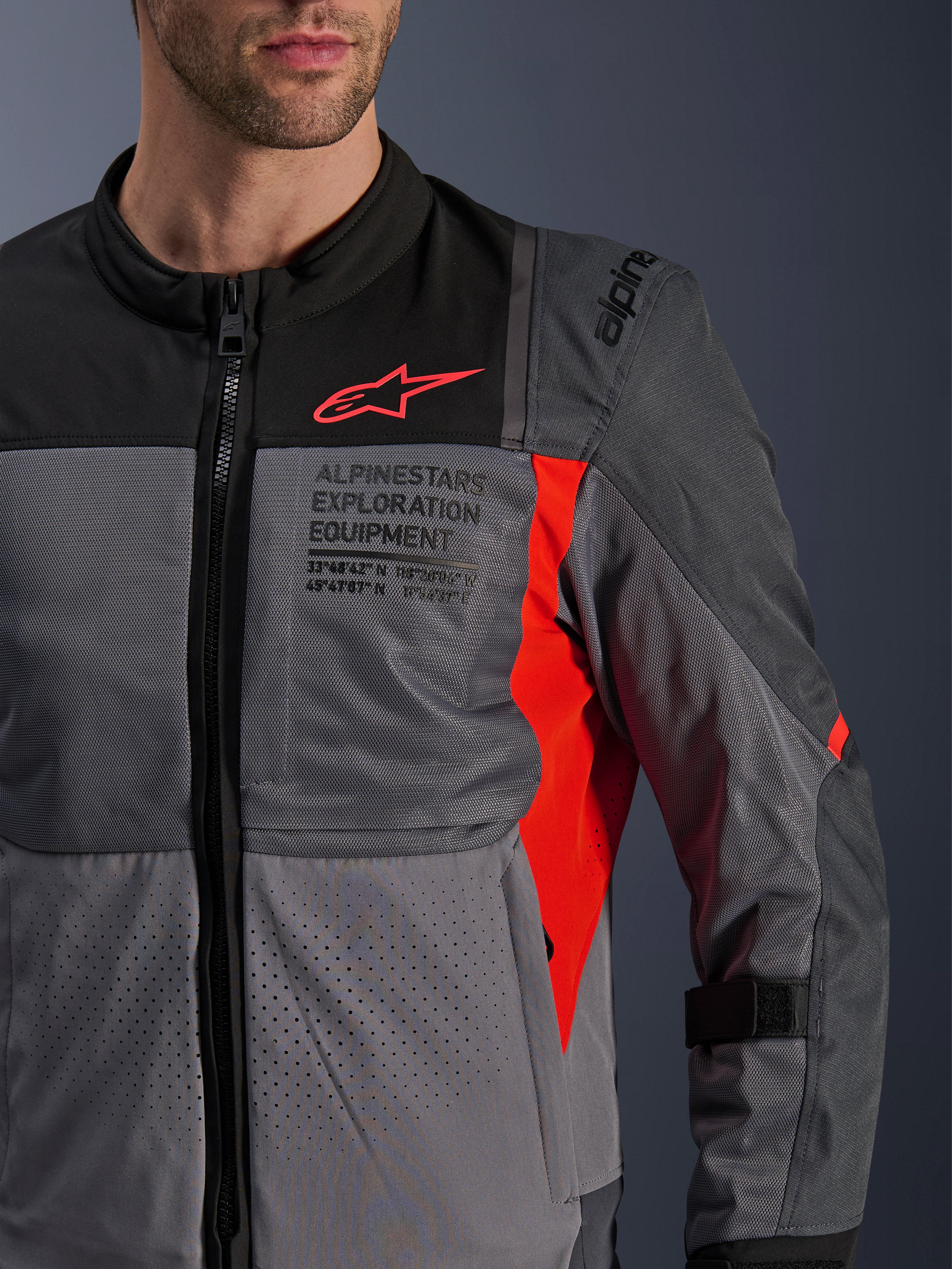 Alpinestars ST-2 Air Jacket, motorcycle textile jacket, Deep Gray and Dark Gray with Bright Red details, close-up featuring breathable mesh panels, laser-perforated fabric, and red star logo with Alpinestars Exploration Equipment branding.