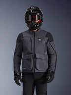 Alpinestars Maxdura Drystar®XF Laminierte Gepanzerte Jacke, Motorradjacke, Dunkelgrau und Schwarz, getragen von einem Fahrer mit schwarzem Helm, Goggles und Handschuhen, mit großen technischen Cargotaschen und ALL TERRA Branding, Adventure-Touring-Ausrüstung