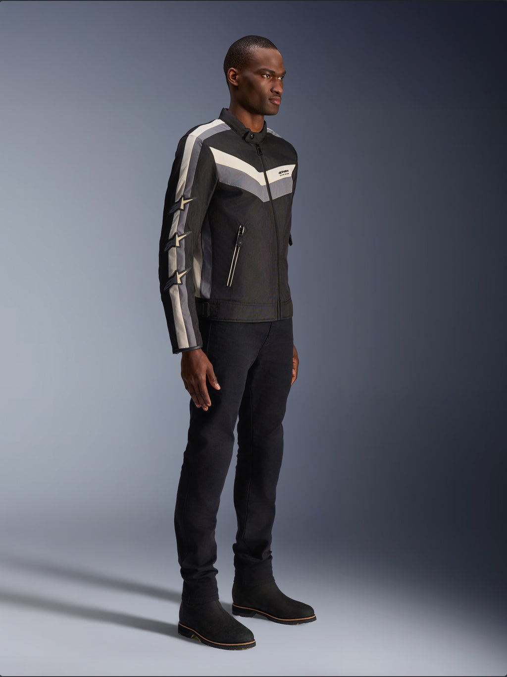 Alpinestars T-Dyno WR Jacke, Textil-Motorradjacke, Schwarz mit dunkelgrauen und ecrufarbenen Chevron-Akzenten, Vintage-inspirierte Biker-Passform, kombiniert mit schwarzer Hose und Stiefeln für einen kompletten Road-Riding-Look