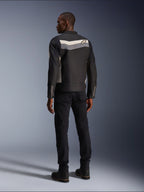 Männliches Model von hinten in der Alpinestars T-Dyno WR Jacke in Black Dark Gray Ecru, Textil-Motorradjacke mit horizontalem Streifen und Stern-Logo auf dem Rücken, kombiniert mit schwarzer Motorradhose und Stiefeln, urbane Motorradausrüstungs-Ästhetik.