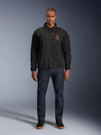 Alpinestars Revved WR Jacke in Schwarz, getragen von einem Modell mit dunkelblauen Jeans und schwarzen Sneakern, Vorderansicht, mit Druckknopfverschluss und einem 3D-Stickerei-Logo auf der Brust, moderne Urban-Motorradausrüstung.