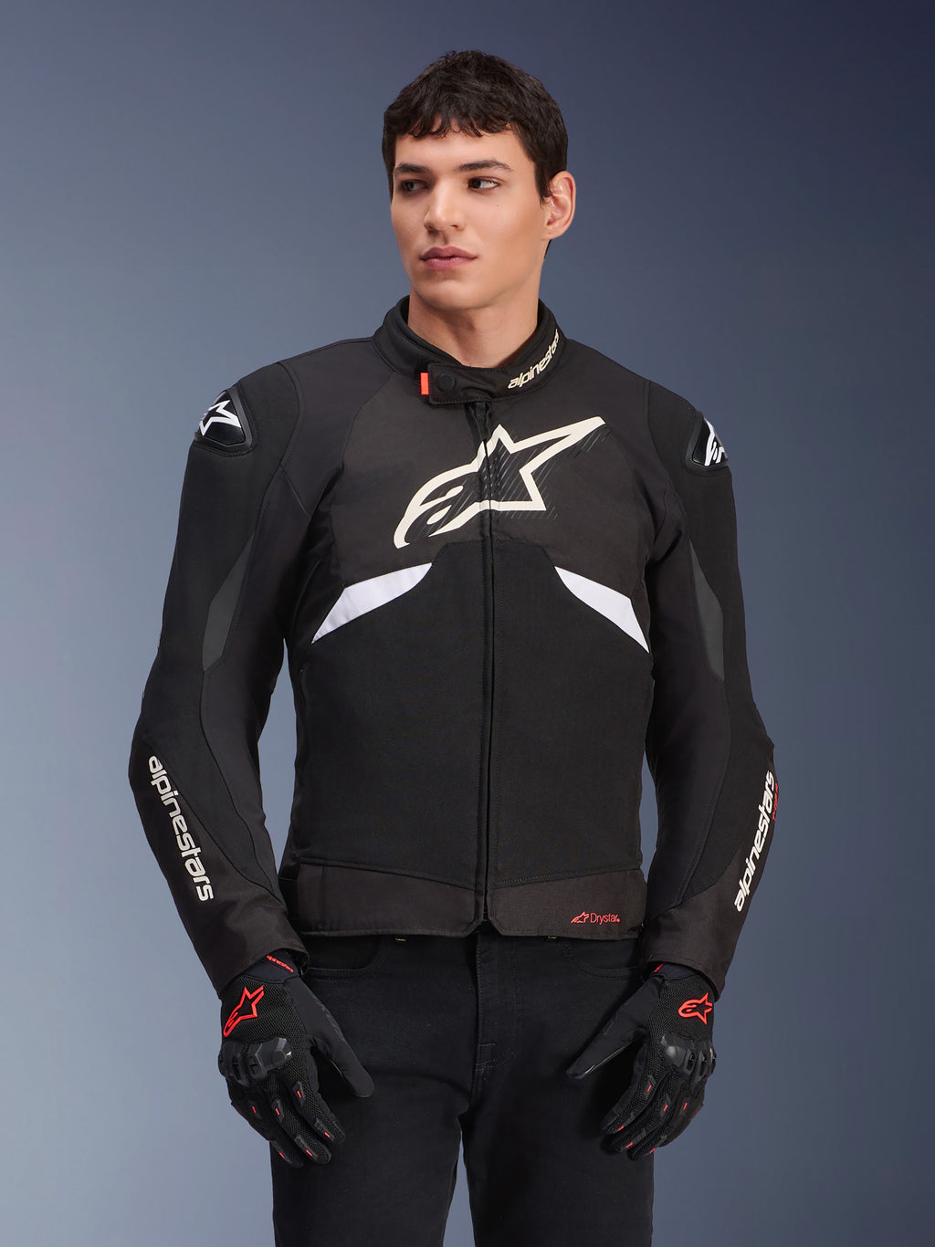 Alpinestars T-GP R V3 Drystar Jacket, Waterproof Sport Textile Jacket, Black and White with Red accents, featuring a large white star logo on the chest and white branding on the sleeves, worn with black and red motorcycle gloves