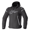 Alpinestars Zaca Waterproof Jacket, Motorcycle Sport Jacket, Black and Dark Gray, featuring a detachable hood, large gray chest logo, light gray accents on shoulders and sides, adjustable waist straps, and front zipper closure, sporty textile construction