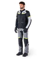 Alpinestars Bogotá Pro Drystar® Jacket, adventure touring motorcycle jacket, Black Ice Gray Yellow Fluo, worn by model with matching pants and black gloves, featuring waterproof textile construction with ventilation panels and fluorescent accents.