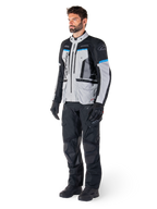Männlicher Motorradfahrer in der Alpinestars Bogotá Pro Drystar® Jacke in Eisgrau, Schwarz und Cyan, kombiniert mit schwarzer technischer Motorradhose und Handschuhen, Adventure-Touring-Ausrüstung für Performance bei jedem Wetter.