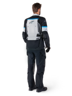 Alpinestars Bogota' Pro Drystar® Jacke, Adventure-Motorradjacke, Ice Gray, Schwarz und Cyan, Rückansicht, getragen mit passender schwarzer Hose und Handschuhen, mit einem großen grauen Rückenteil, schwarzem Alpinestars-Logo und cyanblauen Akzenten.