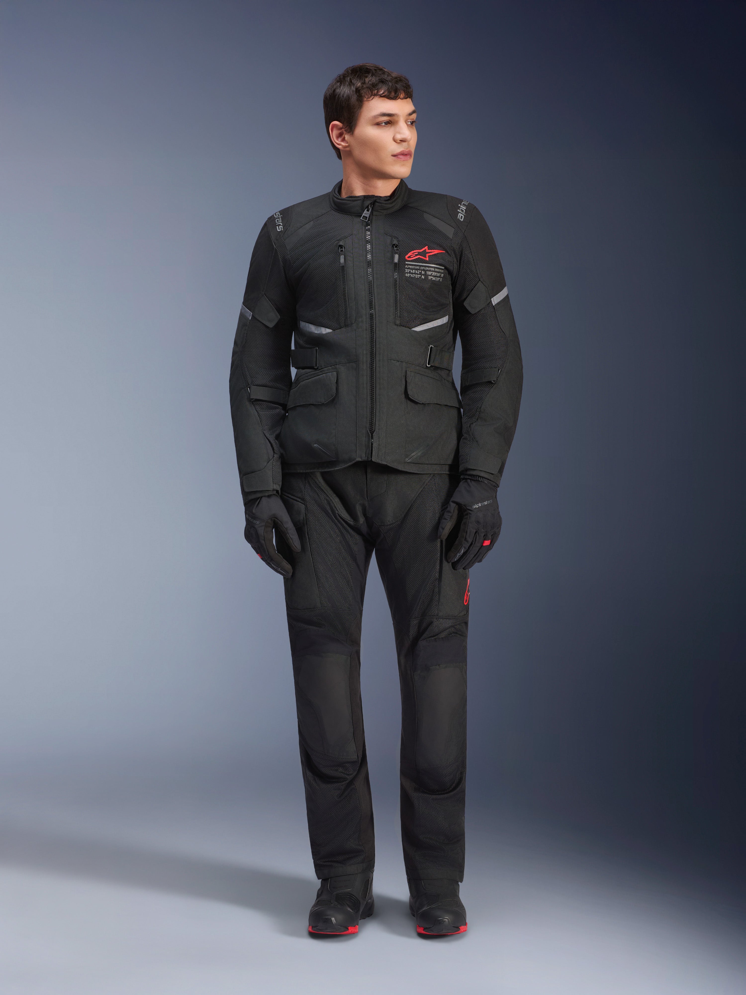Male model wearing Alpinestars Andes Air Drystar® Jacket in Black, adventure touring motorcycle gear with matching pants and gloves, featuring red logo on the chest, mesh ventilation, and functional pockets.