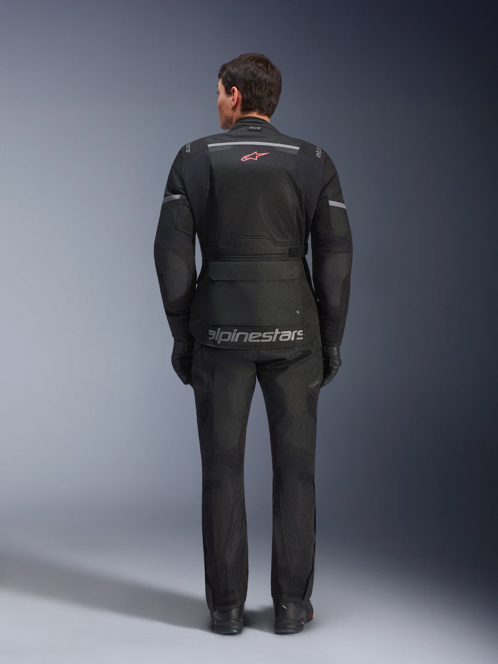 Alpinestars Andes Air Drystar® Jacket and Pants, Black motorcycle touring outfit, rear view of rider, featuring mesh panels, red star logo, and reflective alpinestars branding on the jacket, worn with black gloves and boots.