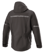 Alpinestars Sirius Drystar® Techshell Jacke, Motorradjacke, Melange Schwarz, Rückansicht mit integrierter Kapuze, Reflektorstreifen mit Alpinestars-Logo, elastischer Taille und verlängerter Rückseite für optimale Abdeckung beim Fahren.
