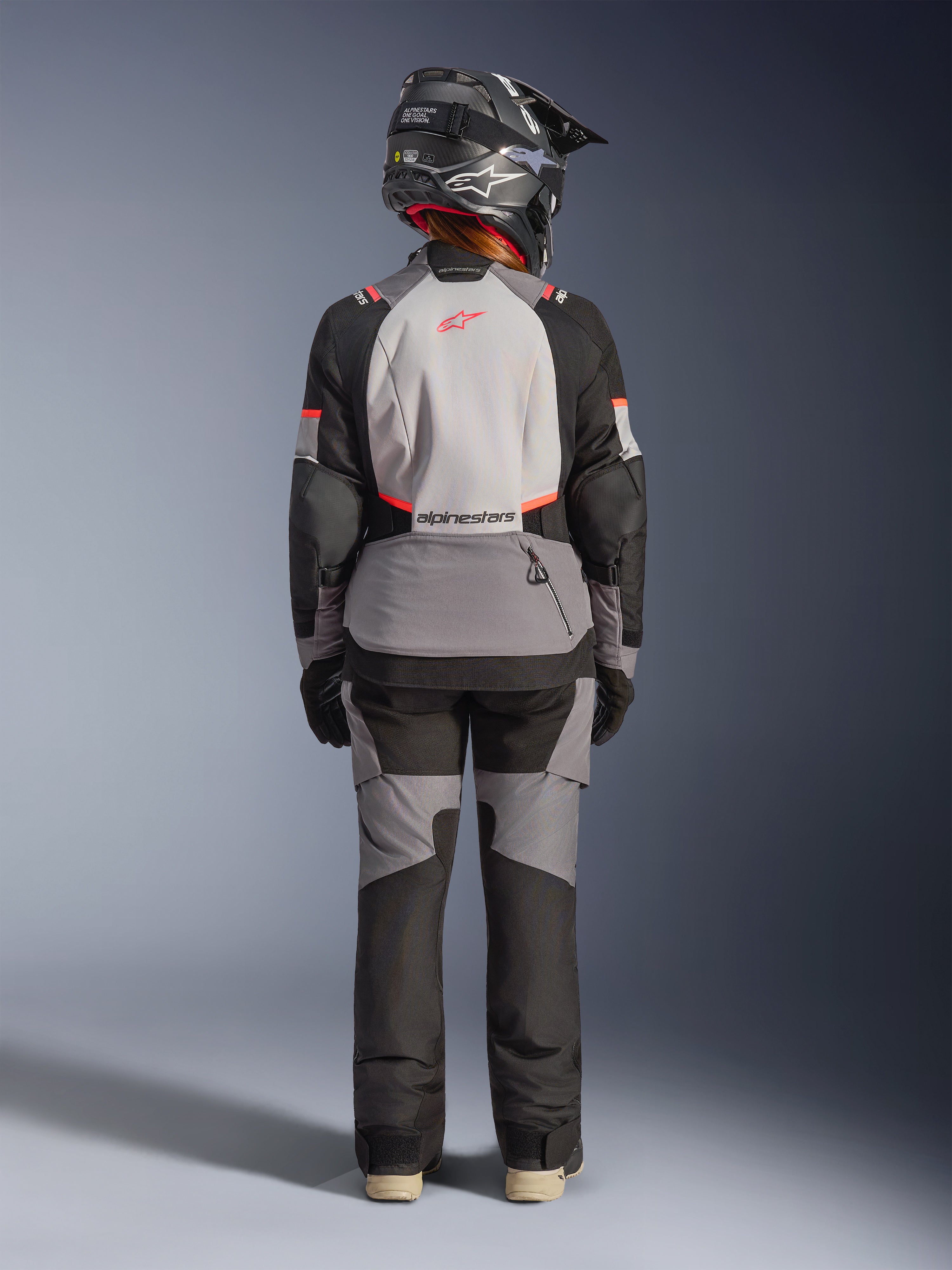 Alpinestars Stella Andes V4 Drystar Jacke, Damen-Adventure-Touring-Motorradjacke, Grau und Schwarz, wasserdichte Textilkonstruktion, Rückansicht am Model mit Helm.