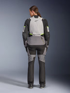 Motorradfahrerin in der Rückansicht, trägt die Alpinestars Stella Andes V4 Drystar® Jacke und passende Hose, Ice Gray und Dark Gray mit schwarzen und Yellow Fluo Akzenten, Adventure-Touring-Motorradausrüstung mit strapazierfähiger Textilkonstruktion und reflektierendem Branding