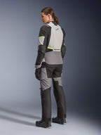 Alpinestars Stella Andes V4 Drystar® Damenjacke, Adventure-Touring Motorradjacke, Ice Gray und Dark Gray mit gelben Fluo-Akzenten, Rückansicht an einem Modell mit passender Textilhose, wasserdichte Konstruktion und verstärkte Ripstop-Einsätze.