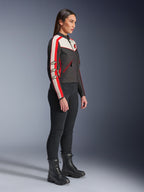 Weibliches Modell in Seitenansicht, Alpinestars Stella T-Dyno WR Jacke in Schwarz, Ecru und Bright Red, Rennstreifen an den Ärmeln und Stern-Logos, kombiniert mit schwarzer Hose und Schnürstiefeln für einen urbanen Motorrad-Stil