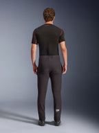 Alpinestars Aeroshell Pants, crossover sports softshell motorcycle pants, Black, rear view worn with a black short-sleeve base layer, featuring a slim fit, pre-curved knees, and white Astars logo on the lower left leg.