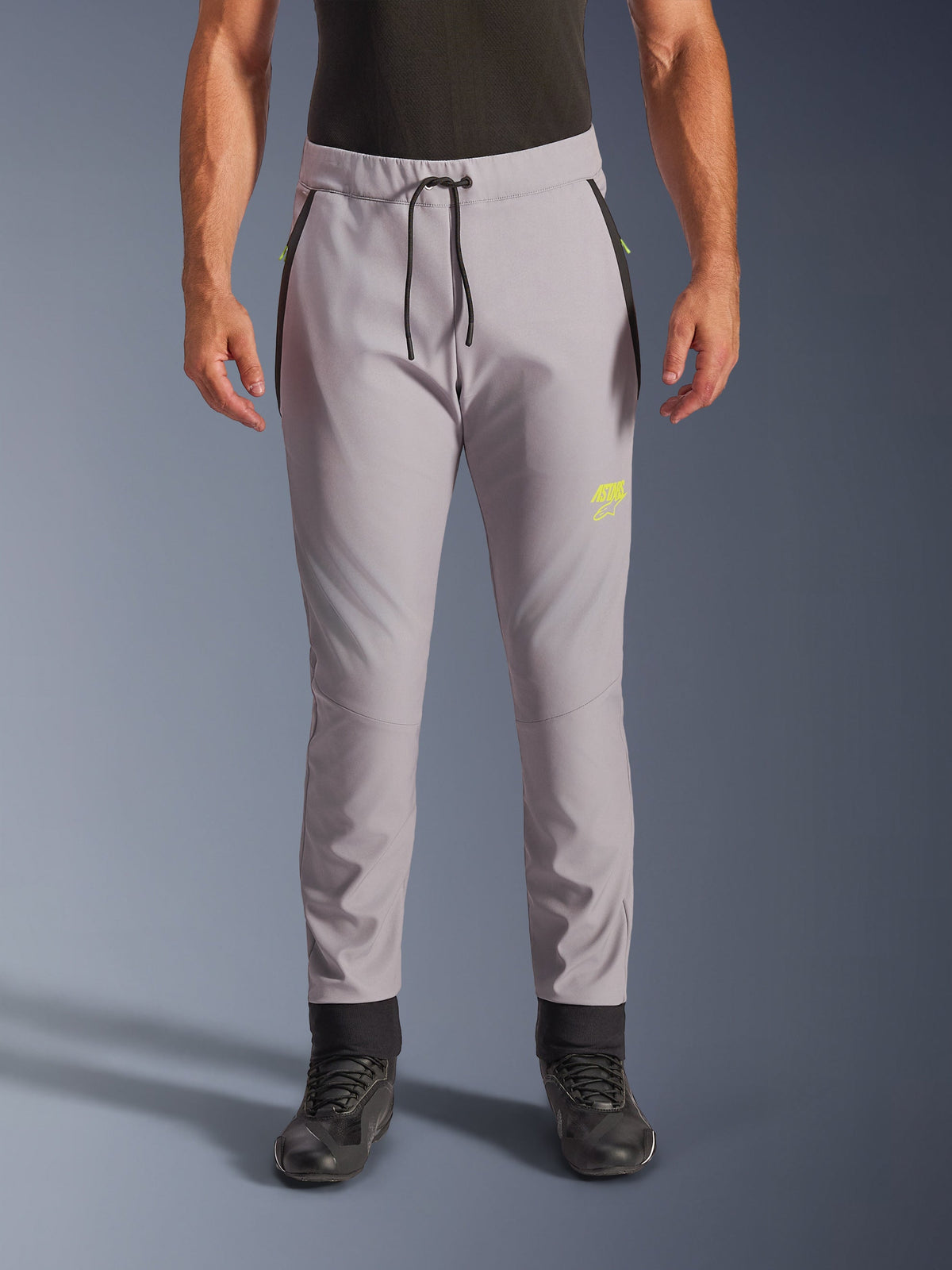 Alpinestars Aeroshell Hose, Mittelgrau und Gelb Fluo, Crossover-Softshell-Motorradhose, schwarzer Kordelzug, eng anliegende Bündchen, gelbes Logo am linken Oberschenkel, vorgeformte Knie, sportliche Jogger-Silhouette