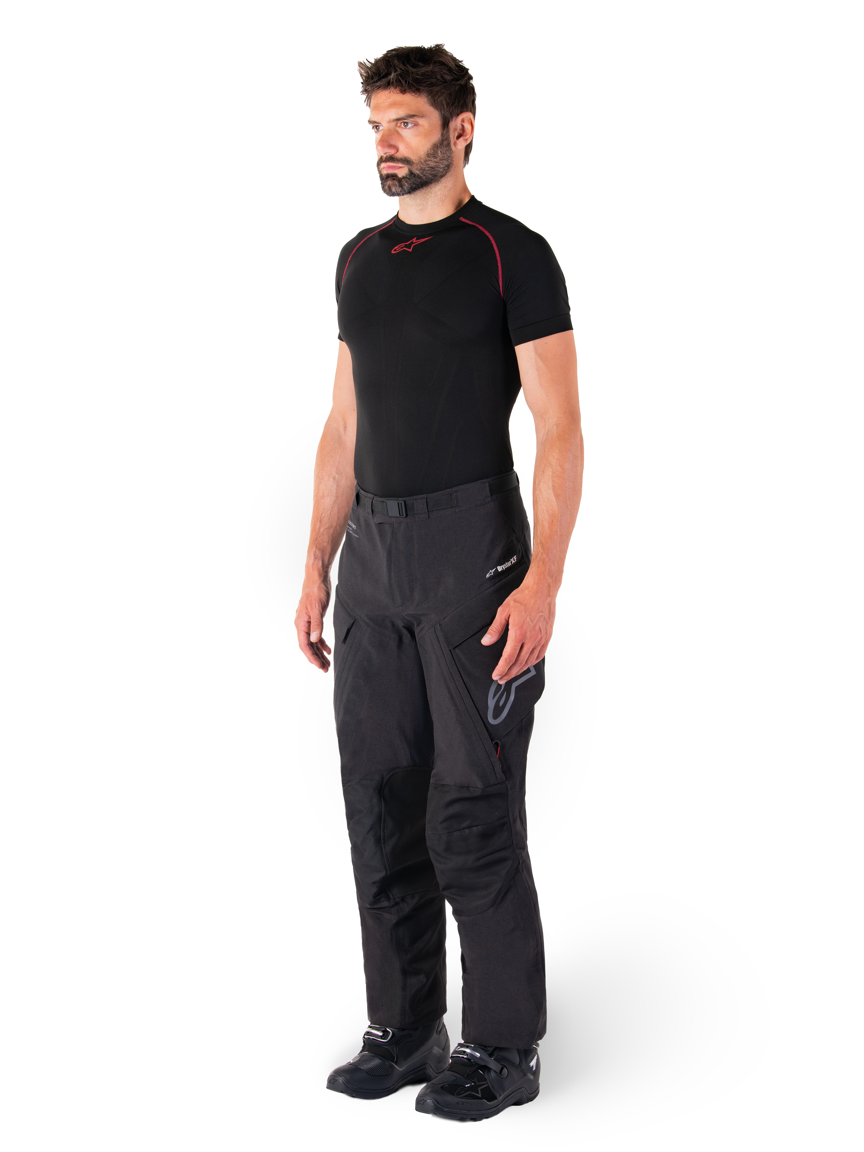 Alpinestars Hyde XT Drystar® Pants, Black adventure touring motorcycle pants worn by a model with a black compression shirt and black boots, featuring technical waterproof construction and Drystar®XF branding.