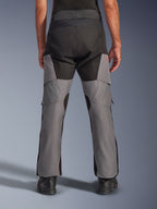 Alpinestars Andes V4 Drystar® Hose, Adventure-Motorradhose, Schwarz und Dunkelgrau, Rückansicht mit verstärktem schwarzen Gesäßbereich und grauen Beinen, mit einem kleinen roten Logo, kombiniert mit schwarzen Motorradstiefeln, strapazierfähige Textilkonstruktion für Allwetter-Touren
