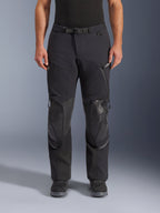 Alpinestars Andes Pro Drystar® XF Hose, Adventure-Touring-Motorradhose in Black Dark Gray, Frontansicht, mit 3-lagiger Laminatkonstruktion, integrierten Knieprotektoren, wasserdichten Reißverschlusstaschen und magnetischem Bundverschluss, kombiniert mit schwarzen Motorradstiefeln.