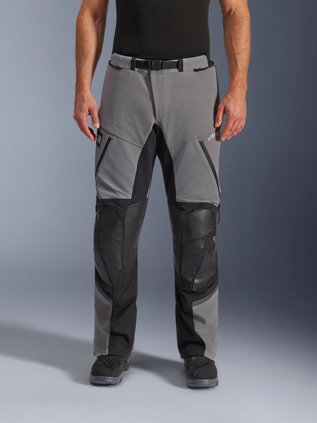 Alpinestars Andes Pro Drystar® XF Hose, Motorradhose, Dunkelgrau und Schwarz, Vorderansicht, mit verstärkten schwarzen Knieeinsätzen, wasserdichten Reißverschlüssen und Gürtel mit Magnetschnalle, getragen mit schwarzen Stiefeln