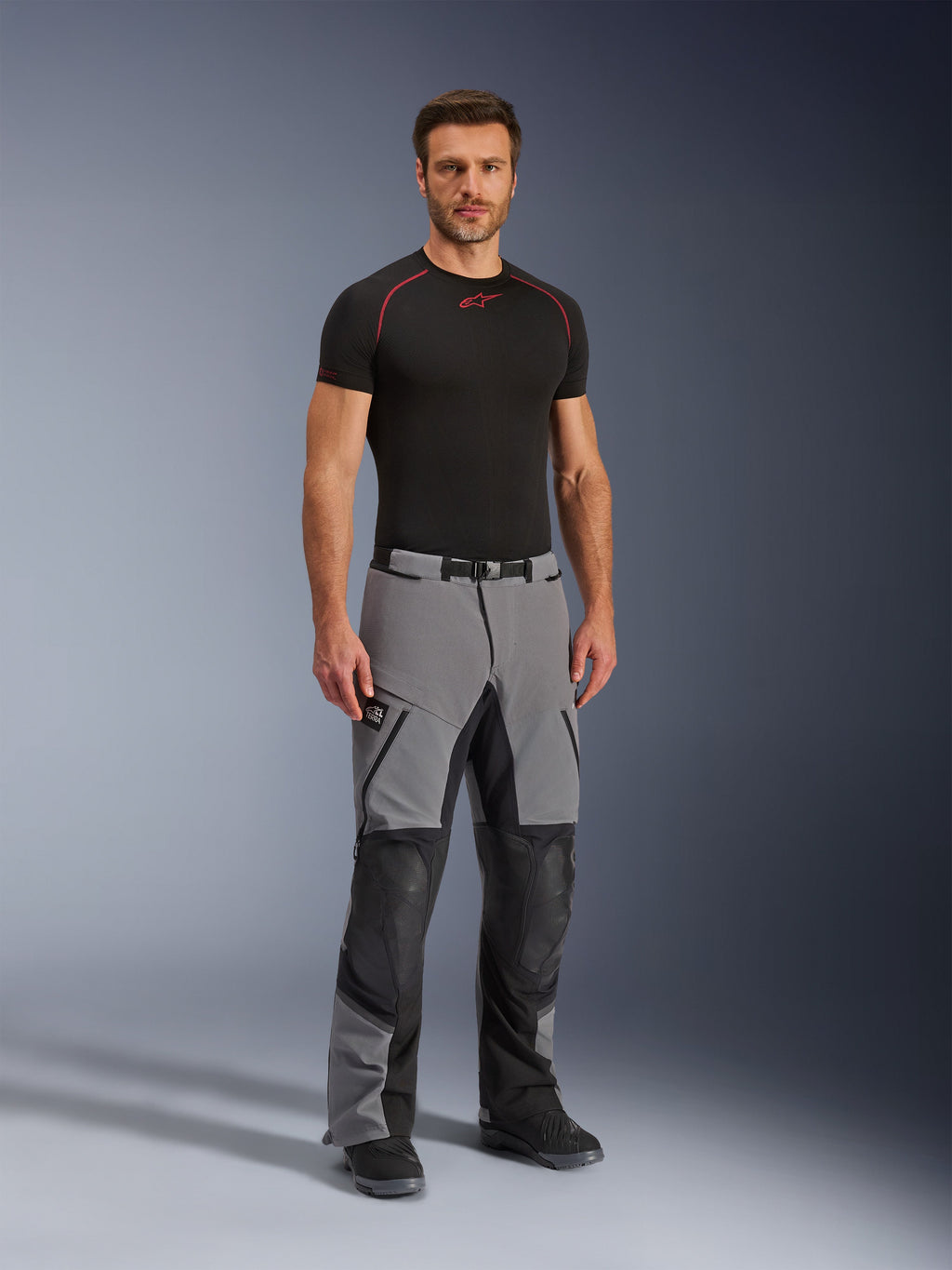 Alpinestars Andes Pro Drystar® XF Pants, Motorcycle Adventure Pants, Dark Gray and Black, worn by a model with a black technical base layer, featuring multi-panel construction with waterproof zippers and reinforced zones for adventure riding.