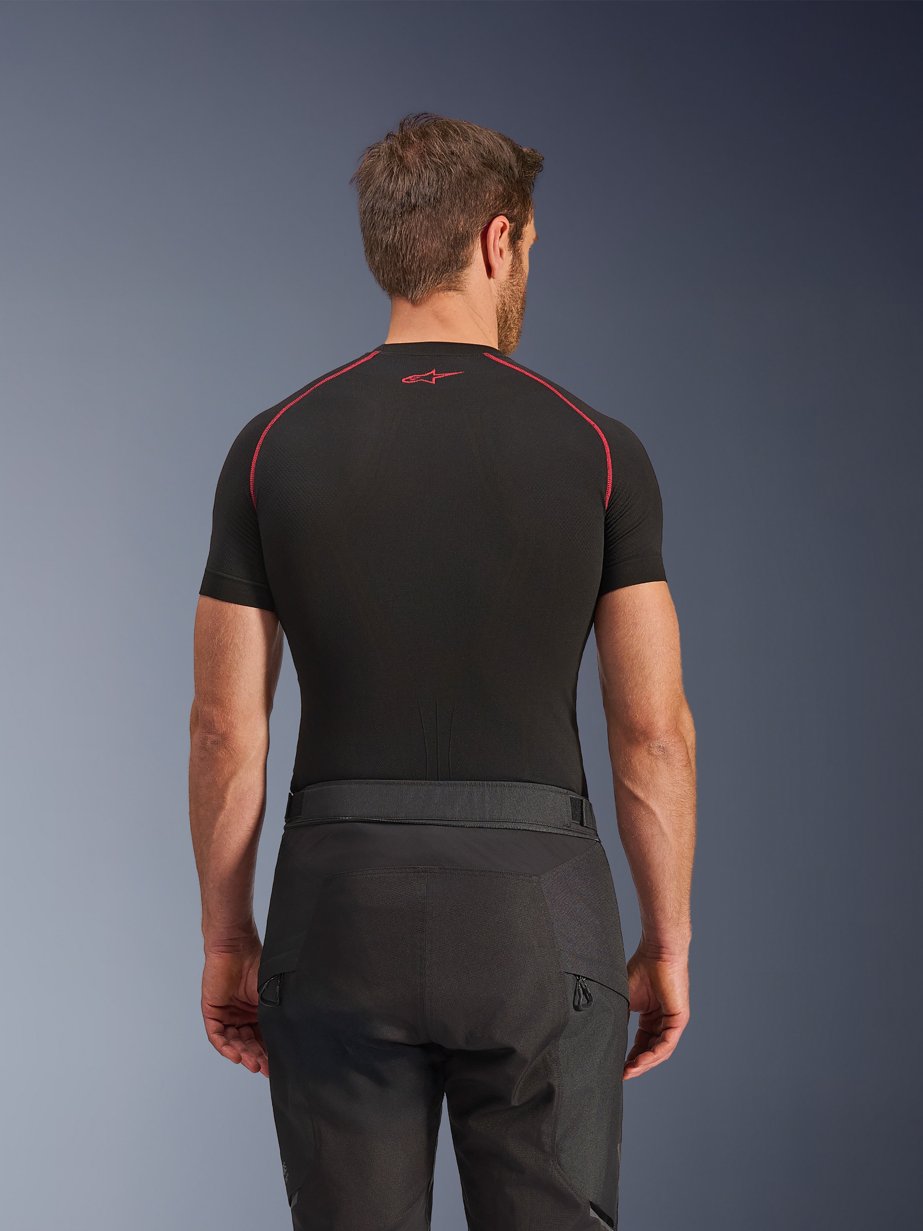 Alpinestars Cusco Drystar® Pants, Black Motorcycle Pants, back view of rider wearing adventure touring gear with a black short-sleeve compression top featuring red stitching, durable ripstop and 600D fabric construction.