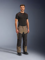 Alpinestars Cusco Drystar® Pants, Adventure Motorcycle Pants, Walnut and Black, worn by a model with a black base layer and boots, featuring large thigh cargo pockets, ventilation zippers, and a rugged dual-tone design.