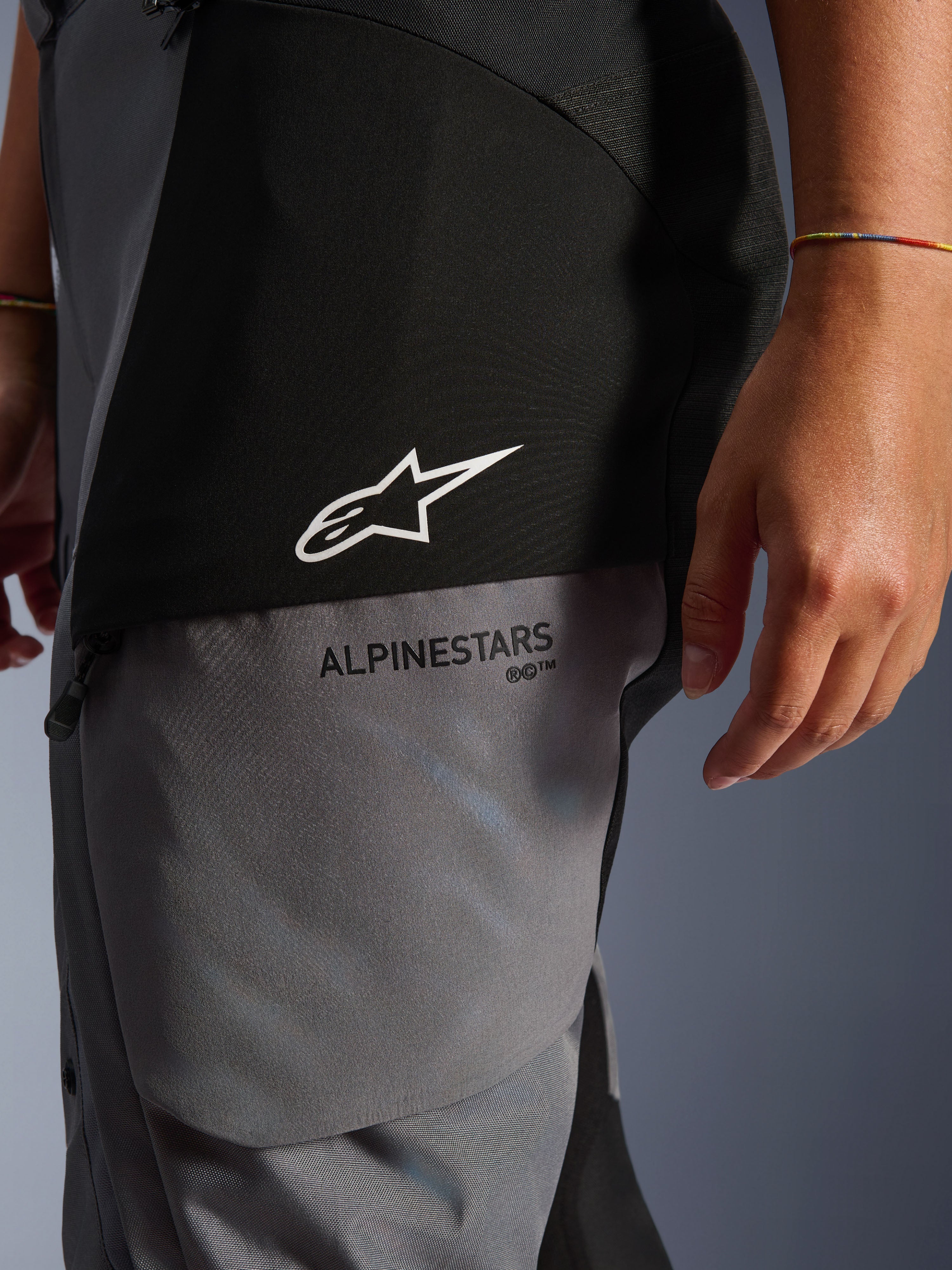 Stella Andes V4 Drystar® Damen-Hose, Schwarz und Dunkelgrau, Nahaufnahme des Oberschenkels mit weißem Stern-Logo und schwarzem Alpinestars-Branding, strapazierfähiges Adventure-Touring-Textilmaterial