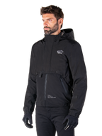 Alpinestars Mootant Waterproof Parka, Black modular motorcycle jacket, worn by a man with black gloves and pants, features a hood, front zipper, and layered utilitarian design, sleek urban aesthetic with logo on chest.