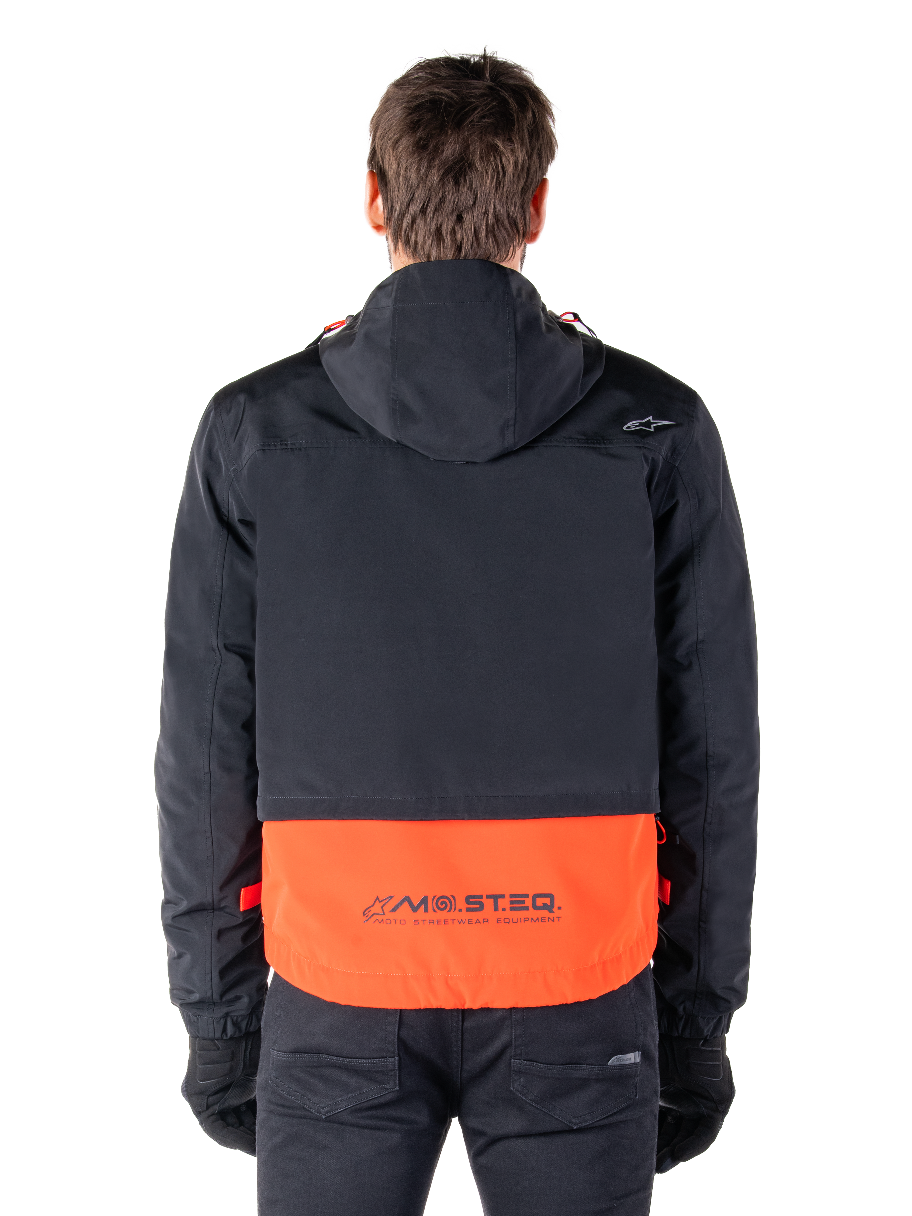 Alpinestars Mootant Waterproof Parka in Spicy Orange and Black, rear view showing black upper with hood and orange lower panel featuring the MO.ST.EQ. wordmark, functional motorcycle streetwear.