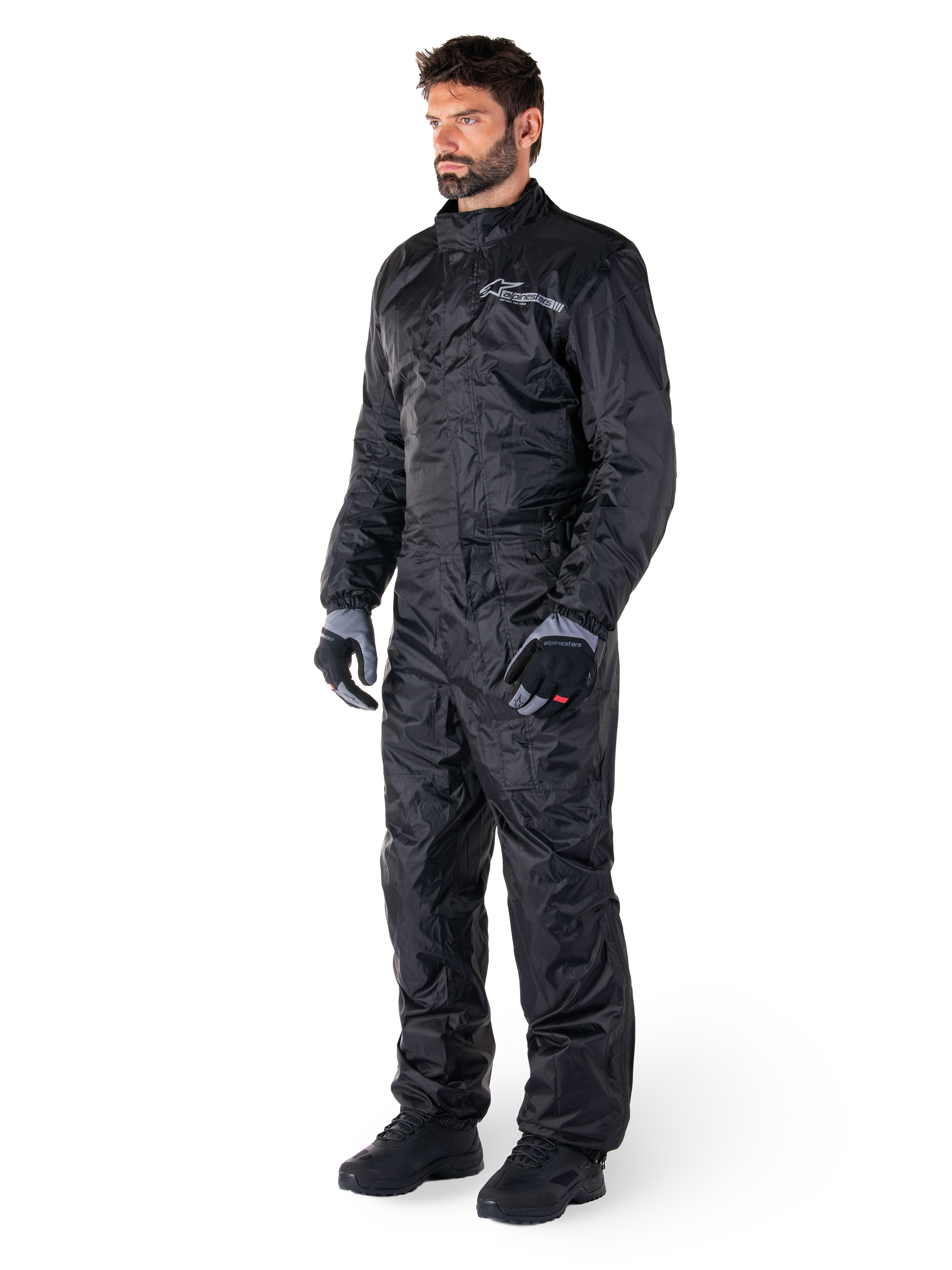Alpinestars Hurricane Rain V2 Anzug, Schwarz, einteiliger wasserdichter Motorrad-Regenanzug, getragen mit Handschuhen und Stiefeln, mit reflektierendem Alpinestars-Branding auf der Brust, leichtes Design für Schutz bei nassem Wetter