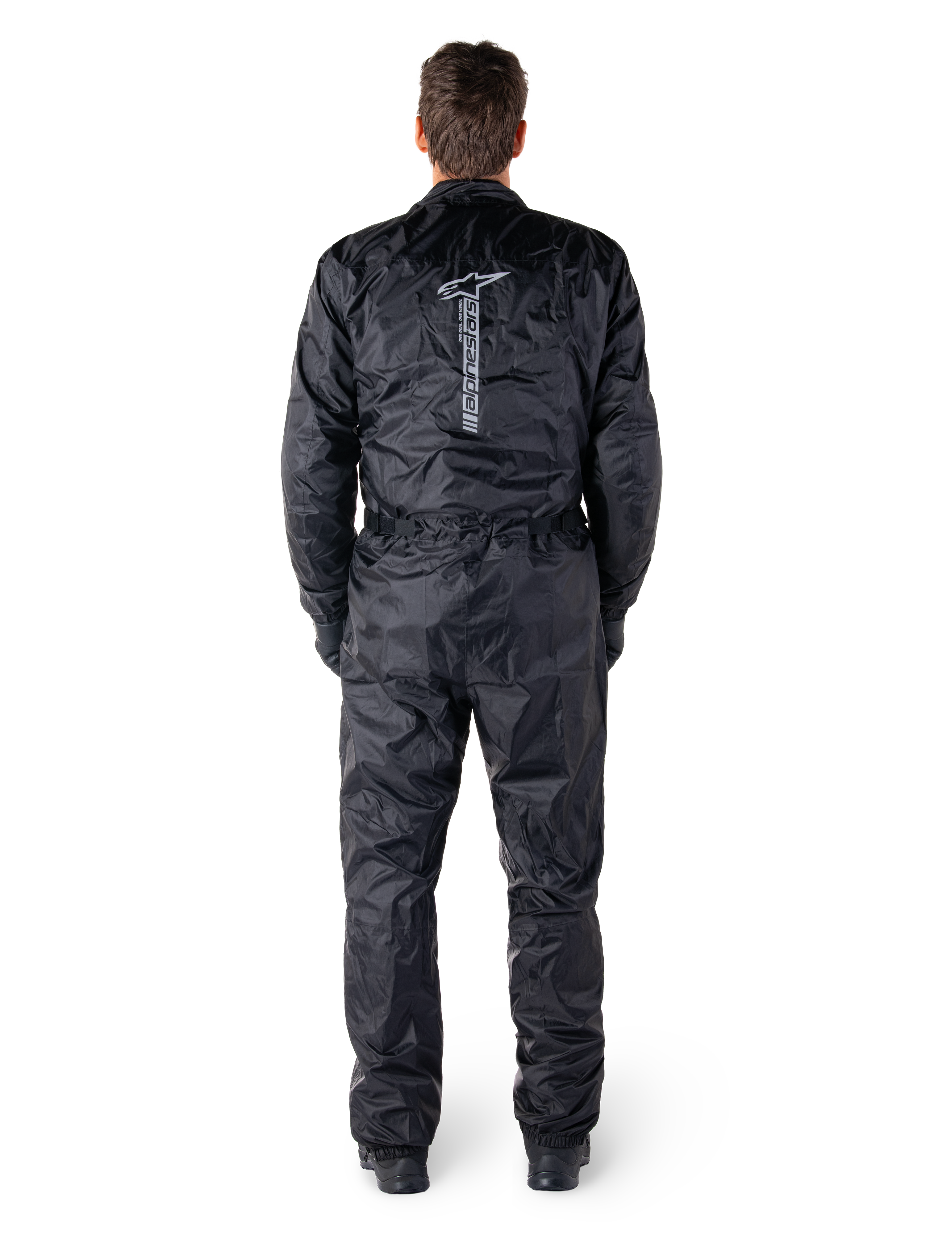 Alpinestars Hurricane Rain V2 Anzug, schwarzer einteiliger wasserdichter Motorrad-Regenanzug, Rückansicht mit großem vertikalem Alpinestars-Schriftzug und Logo, leichtes Gewebe mit elastischem Bund und Bündchen, konzipiert für Schutz bei nassem Wetter.