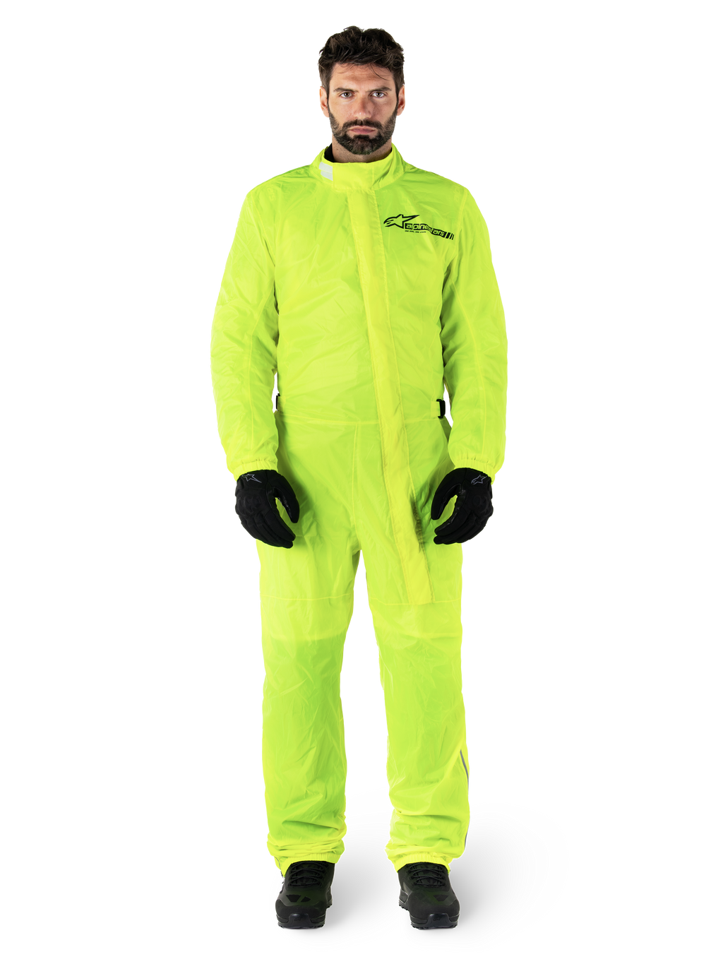 Alpinestars Hurricane Rain V2 Anzug, Motorrad-Regenanzug, Gelb Fluo, männliches Model in Ganzkörperschutz mit schwarzen Handschuhen und Stiefeln, hochgeschlossener Kragen mit vorderer Windschutzleiste, reflektierendes Logo auf der Brust, gut sichtbare wasserdichte Ausrüstung