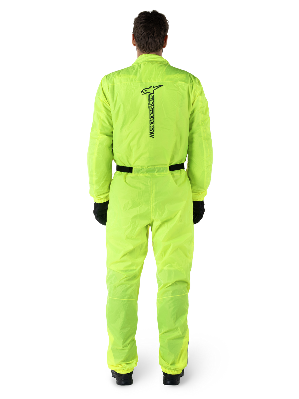 Alpinestars Hurricane Rain V2 Anzug, einteiliger Motorrad-Regenanzug, Gelb Fluo, Rückansicht mit vertikalem schwarzem Alpinestars-Branding, elastischer Bund und Ärmelbündchen, getragen mit schwarzen Handschuhen und Stiefeln, wasserdichte und windabweisende Fahrausrüstung