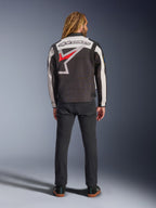 Alpinestars Axton Jacke, Motorradjacke, Schwarz, Off-White und Bright Red, Rückansicht an einem Model, mit einem großen Alpinestars-Sternlogo auf dem Rücken, Off-White-Ärmeleinsätzen, getragen mit einer schwarzen Hose, von Vintage-Rennsportbekleidung inspiriertes Design