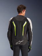 Alpinestars AST V3 Air Jacket, Black Silver Yellow Fluo, rear view on model, textile motorcycle jacket featuring dual tech mesh ventilation panels, vertical neon yellow stripes, silver sleeves, and a white Alpinestars logo on the lower back.