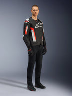 Alpinestars T-GP Air Jacket, Black Red Fluo, worn by model with black riding pants and gloves, featuring laser-perforated textile panels, white Alpinestars branding, and red accents, sport motorcycle jacket for warm weather road riding