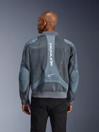 Alpinestars Flight Air Jacke in Storm Gray, Rückansicht an einem Model, urbane Motorradjacke mit erweiterten 3D-Mesh-Einsätzen, vertikalem Alpinestars-Branding auf dem Rücken sowie geripptem Saum und Kragen im Bomber-Stil.
