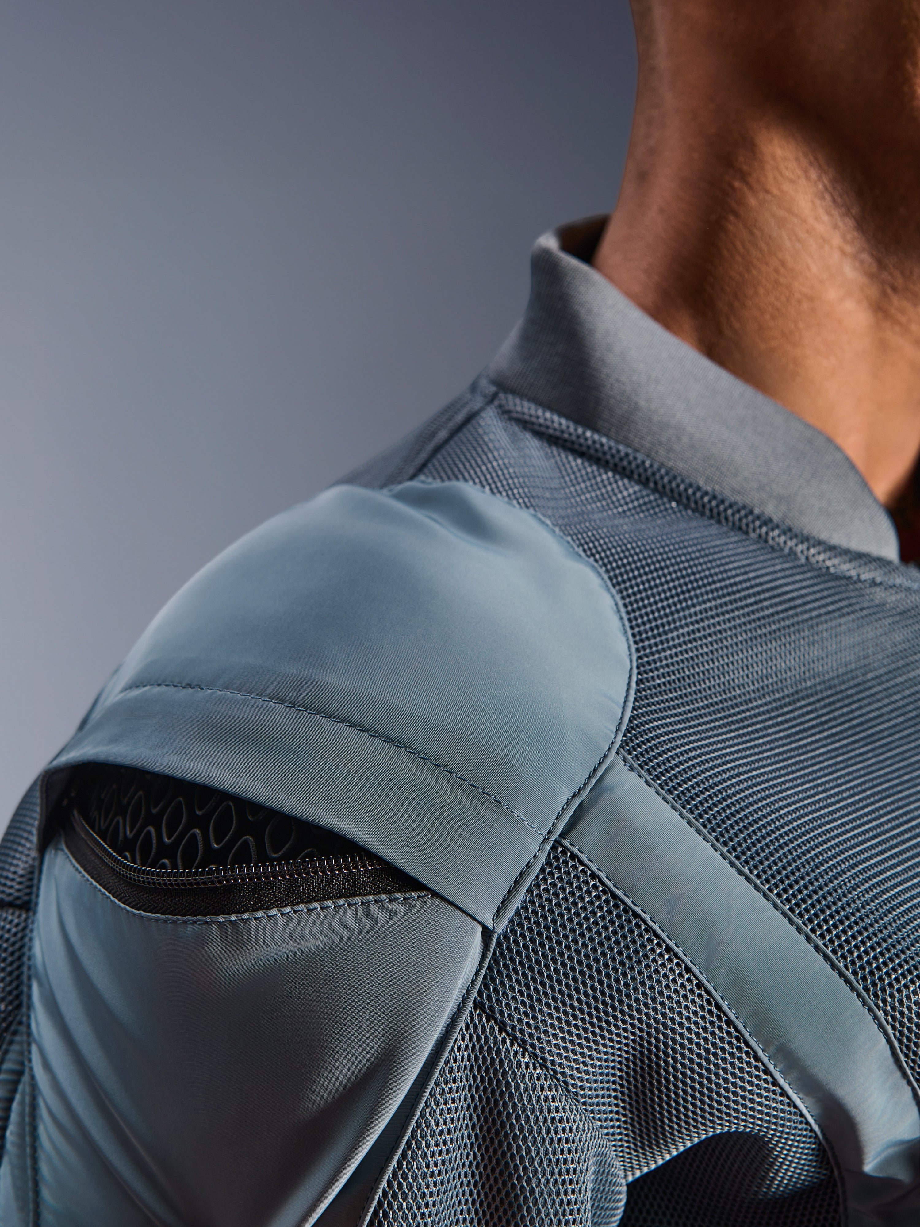 Nahaufnahme der Alpinestars Flight Air Jacke in Storm Gray, die die externe Schulterprotektorentasche mit sichtbarem Wabenprotektor, 3D-Mesh-Belüftungseinsätze und den gerippten Kragen für technisches urbanes Motorradfahren hervorhebt