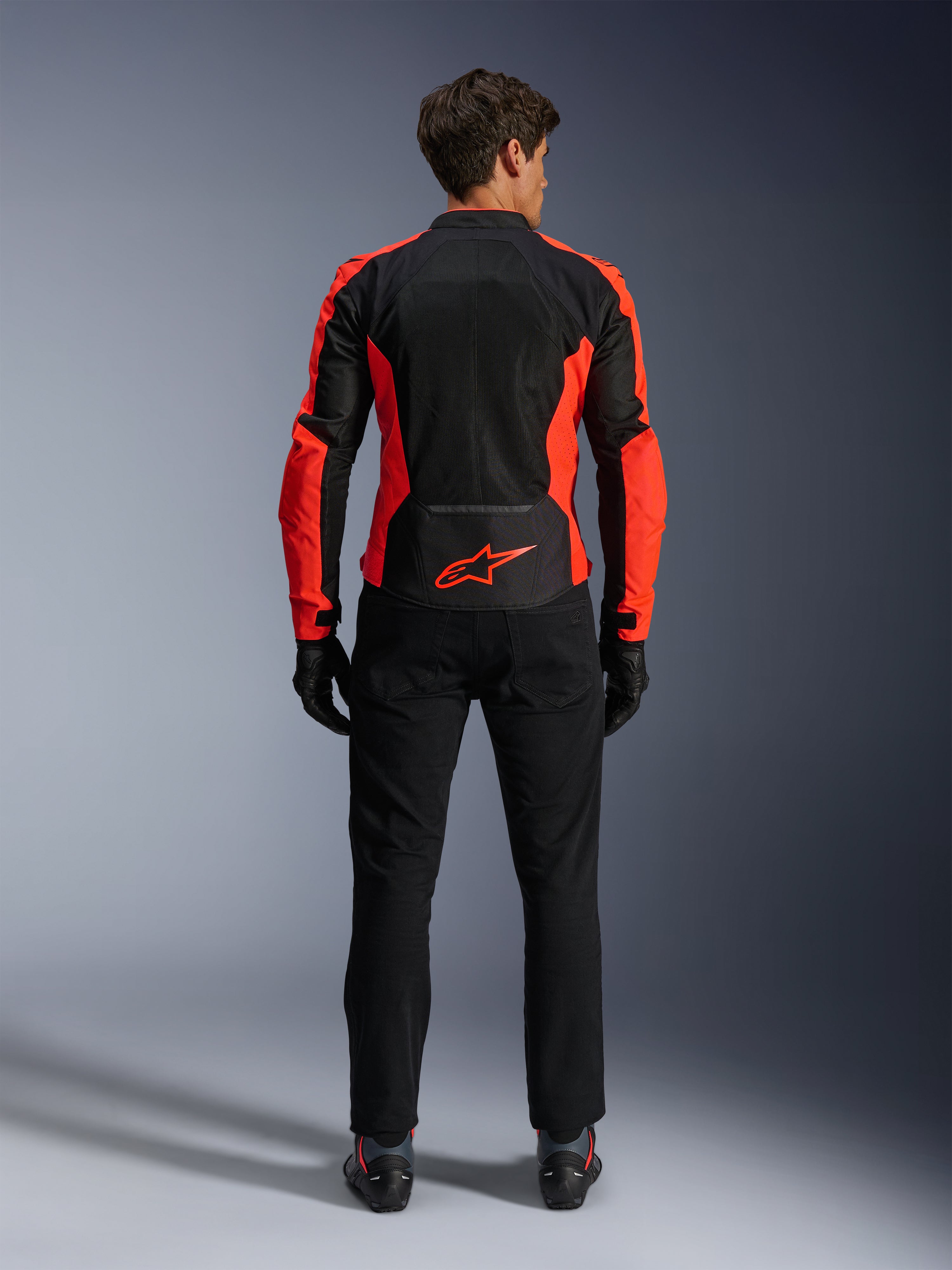 Alpinestars Viper Air V4 Jacket, Red Fluo and Black, back view showing large tech mesh panels and bright red fluorescent side accents, red Alpinestars logo on the lower back, worn with black riding pants and gloves.